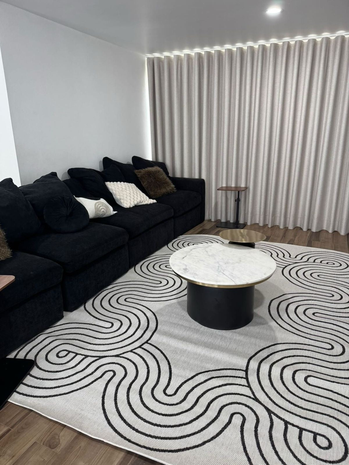 Indoor/Outdoor Ivory Rug with Black Geometric Swirl and Live Edge Design.