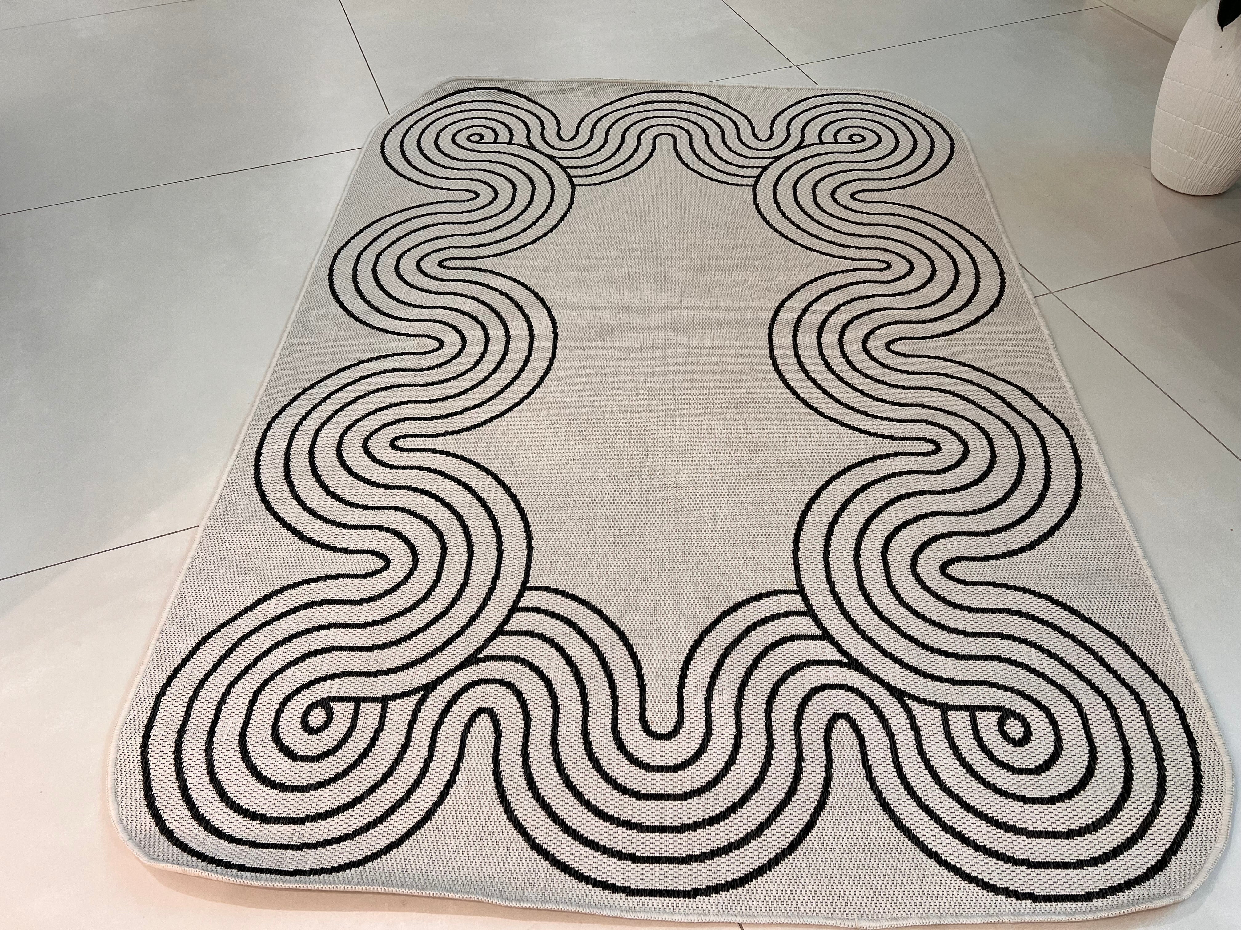 Indoor/Outdoor Ivory Rug with Black Geometric Swirl and Live Edge Design.