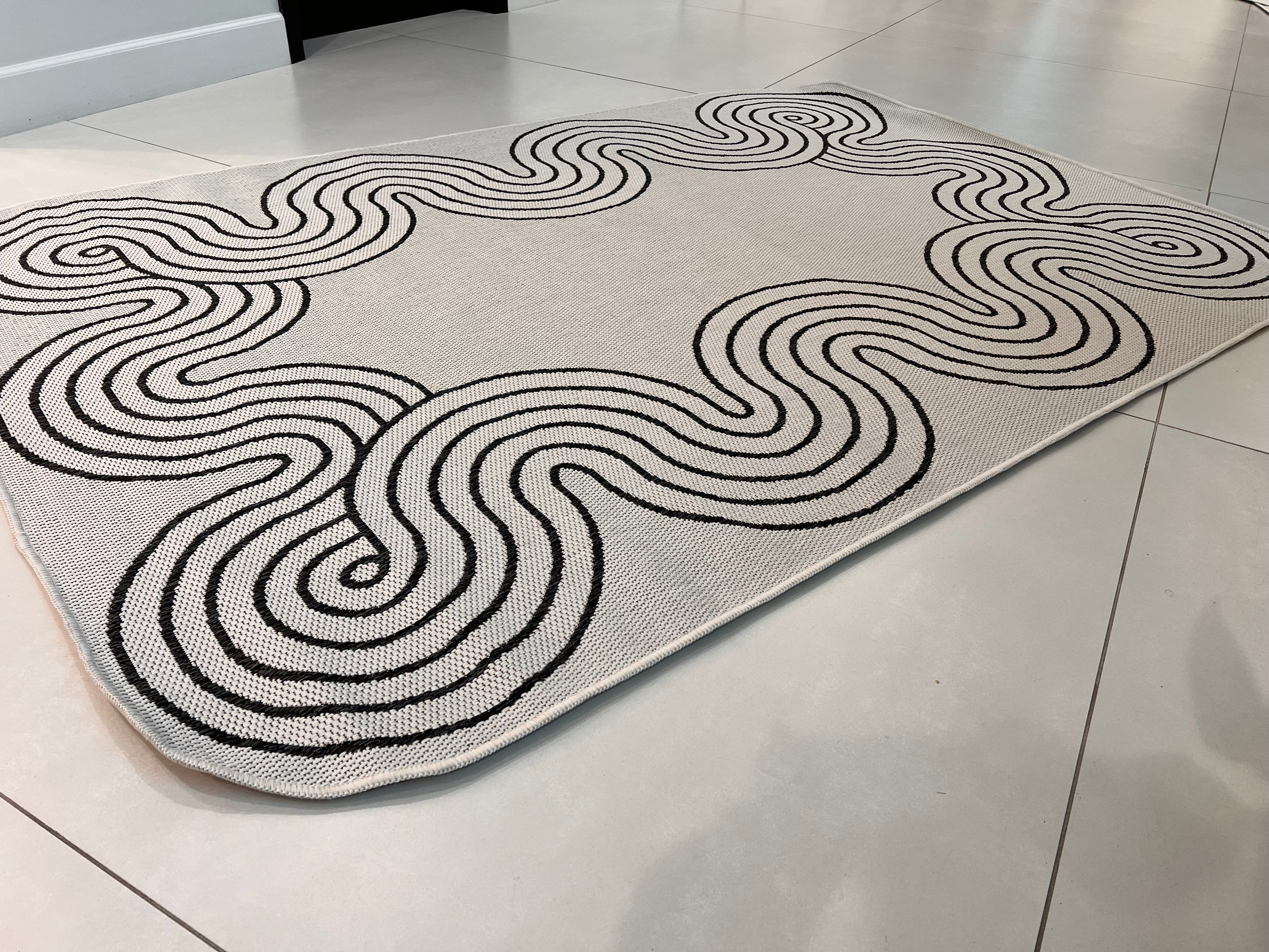 Indoor/Outdoor Ivory Rug with Black Geometric Swirl and Live Edge Design.