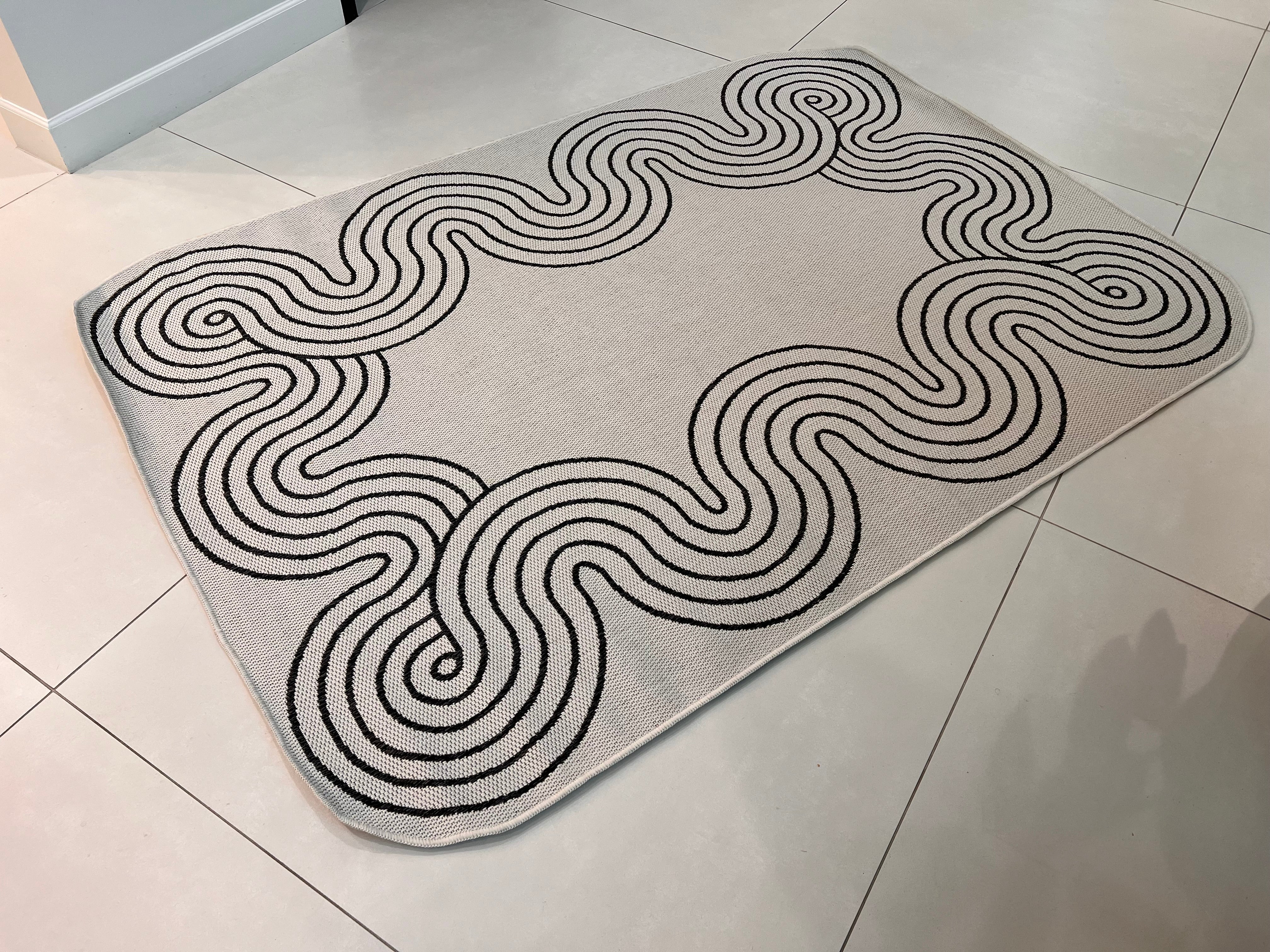 Indoor/Outdoor Ivory Rug with Black Geometric Swirl and Live Edge Design.