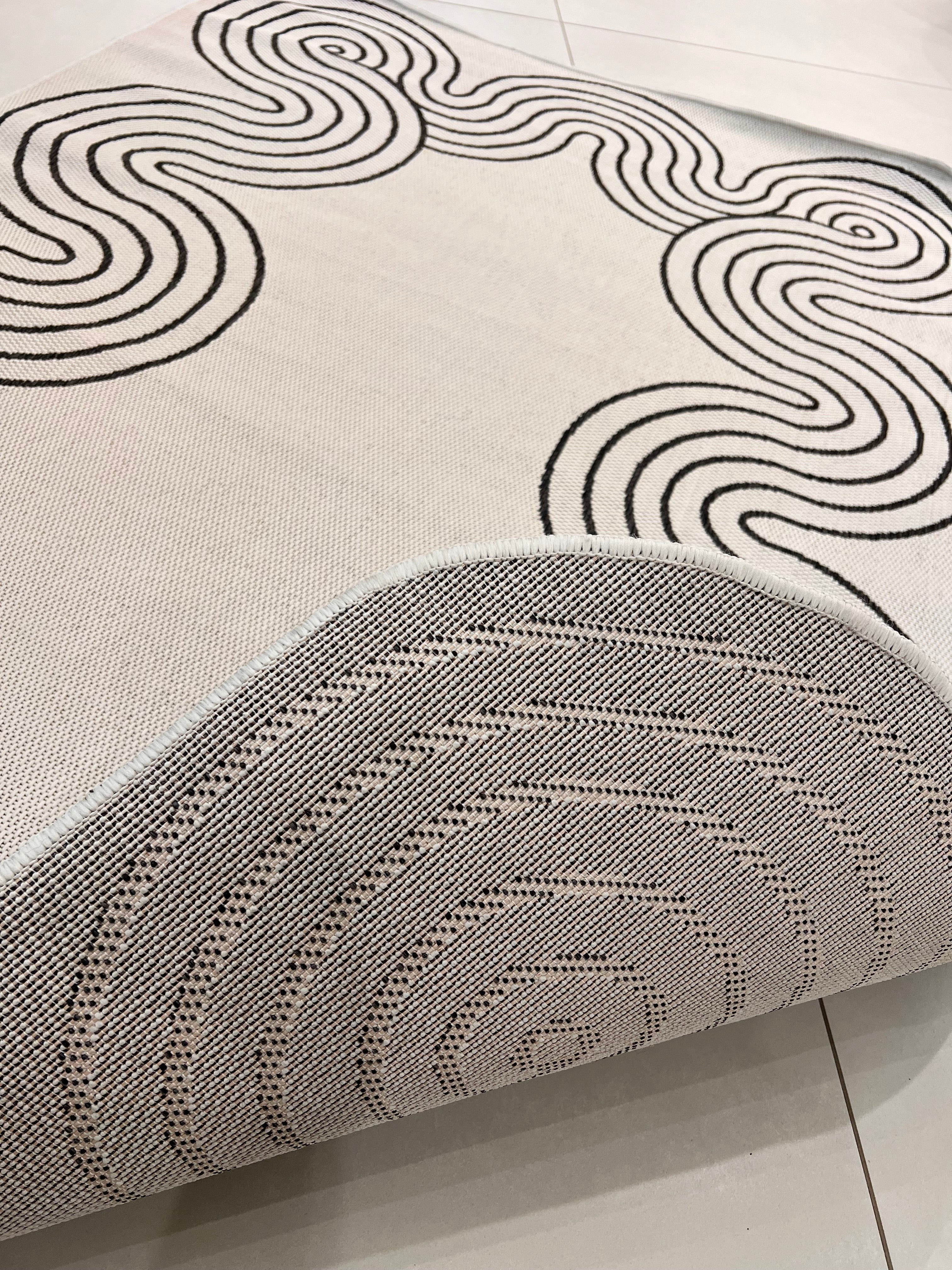 Indoor/Outdoor Ivory Rug with Black Geometric Swirl and Live Edge Design.