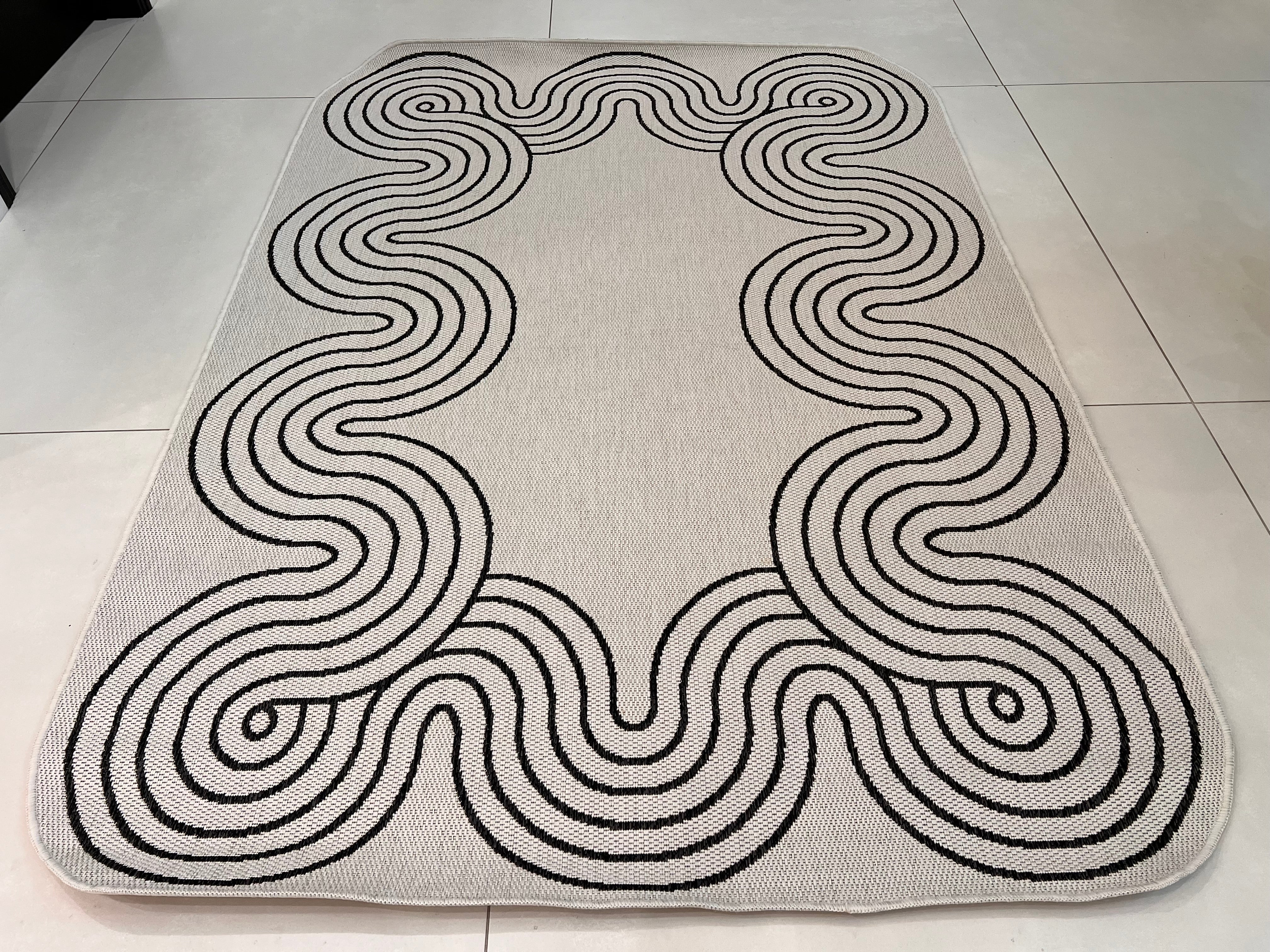 Indoor/Outdoor Ivory Rug with Black Geometric Swirl and Live Edge Design.