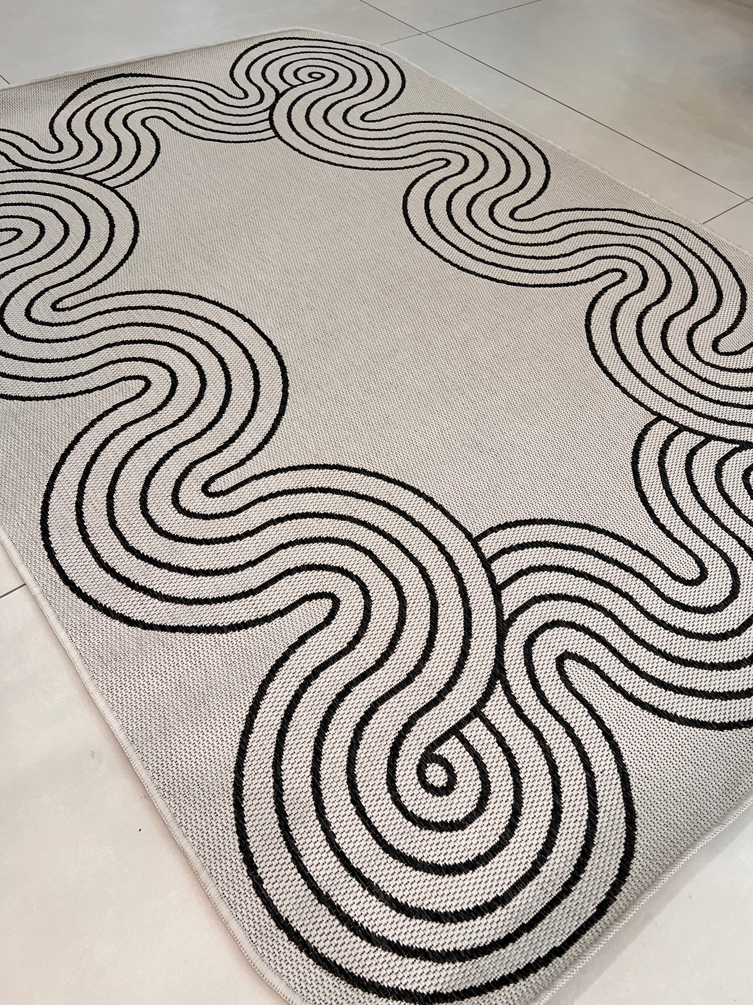 Indoor/Outdoor Ivory Rug with Black Geometric Swirl and Live Edge Design.